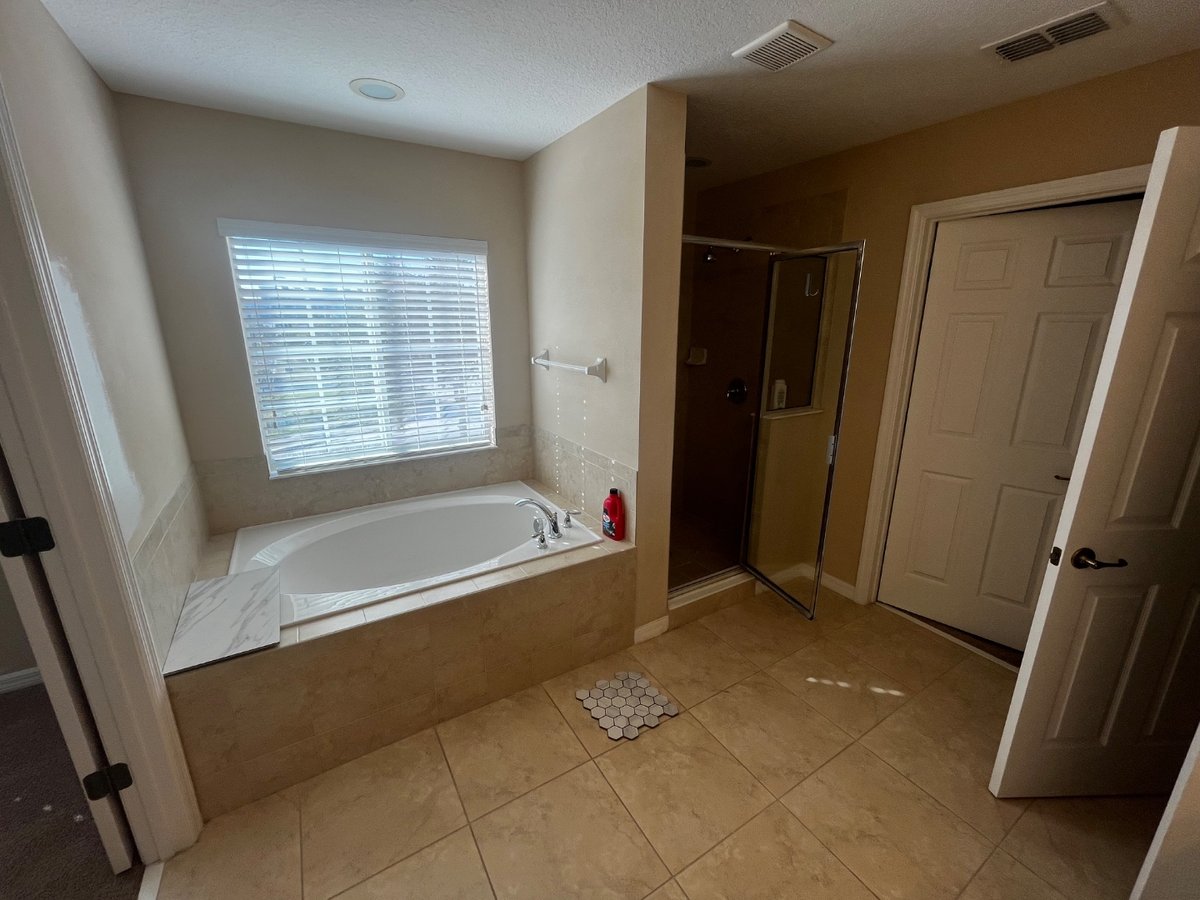 Before: dated bathroom with beige tile and old shower enclosure