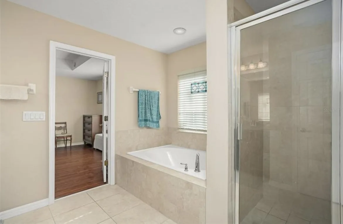 Before: cramped builder-grade Sanford primary bath with a garden tub and dated framed-glass shower